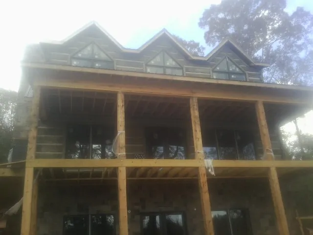 Dormers and porch framing on a large log home under construction — Roof Coating work by our crew in Davenport